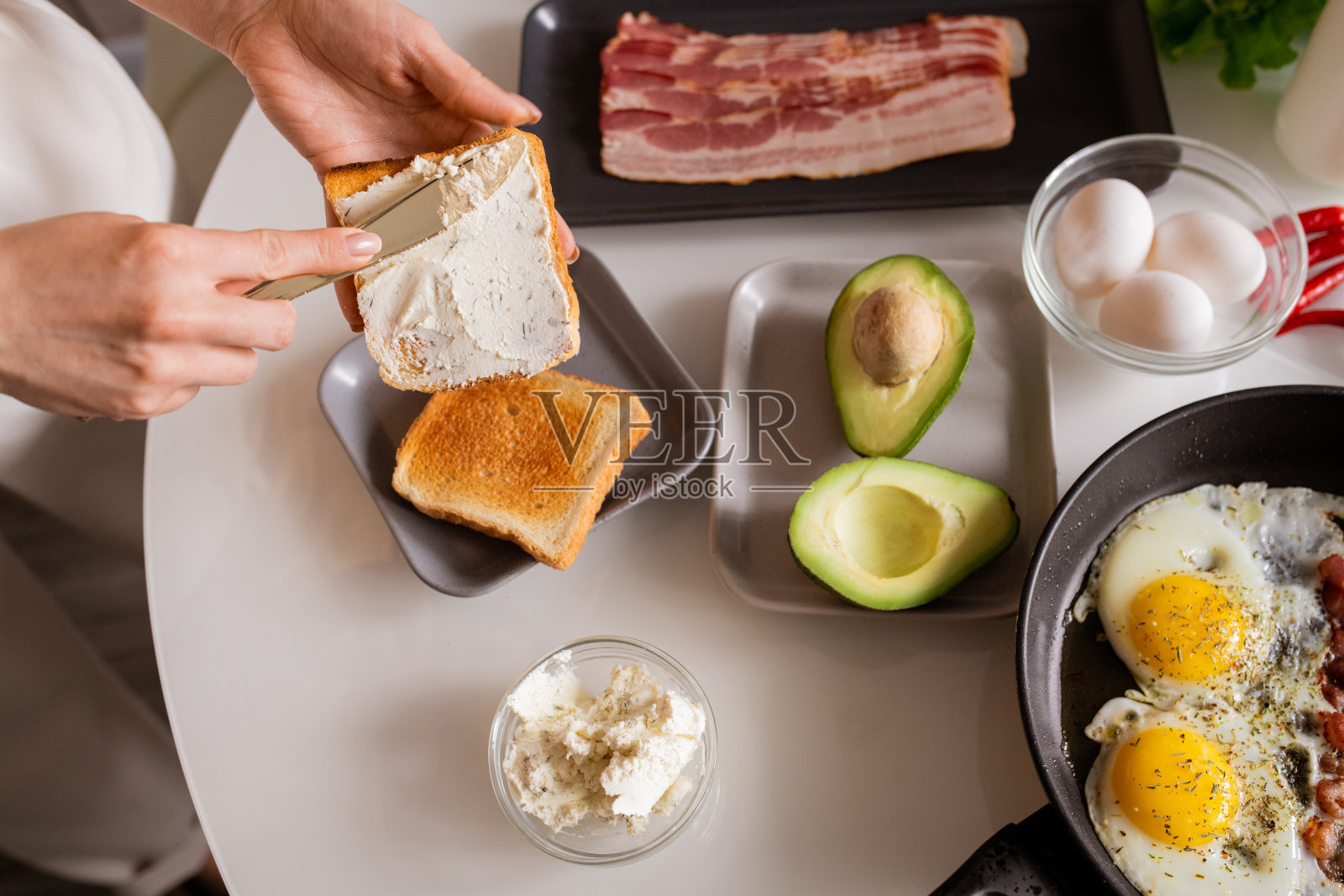 年轻女性的双手在烤面包上涂抹黄油或奶酪照片摄影图片