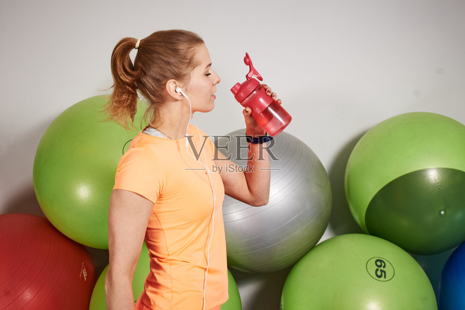 苗条的运动员年轻女子在健身俱乐部运动服装与水瓶。照片摄影图片