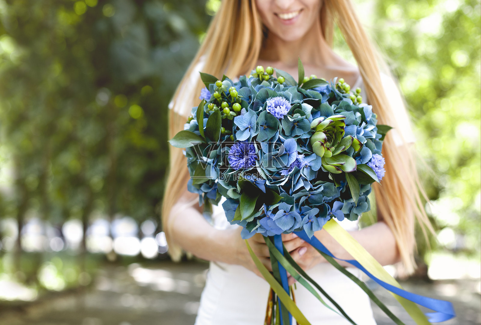 快乐的女人捧着一束绿色和蓝色的花照片摄影图片