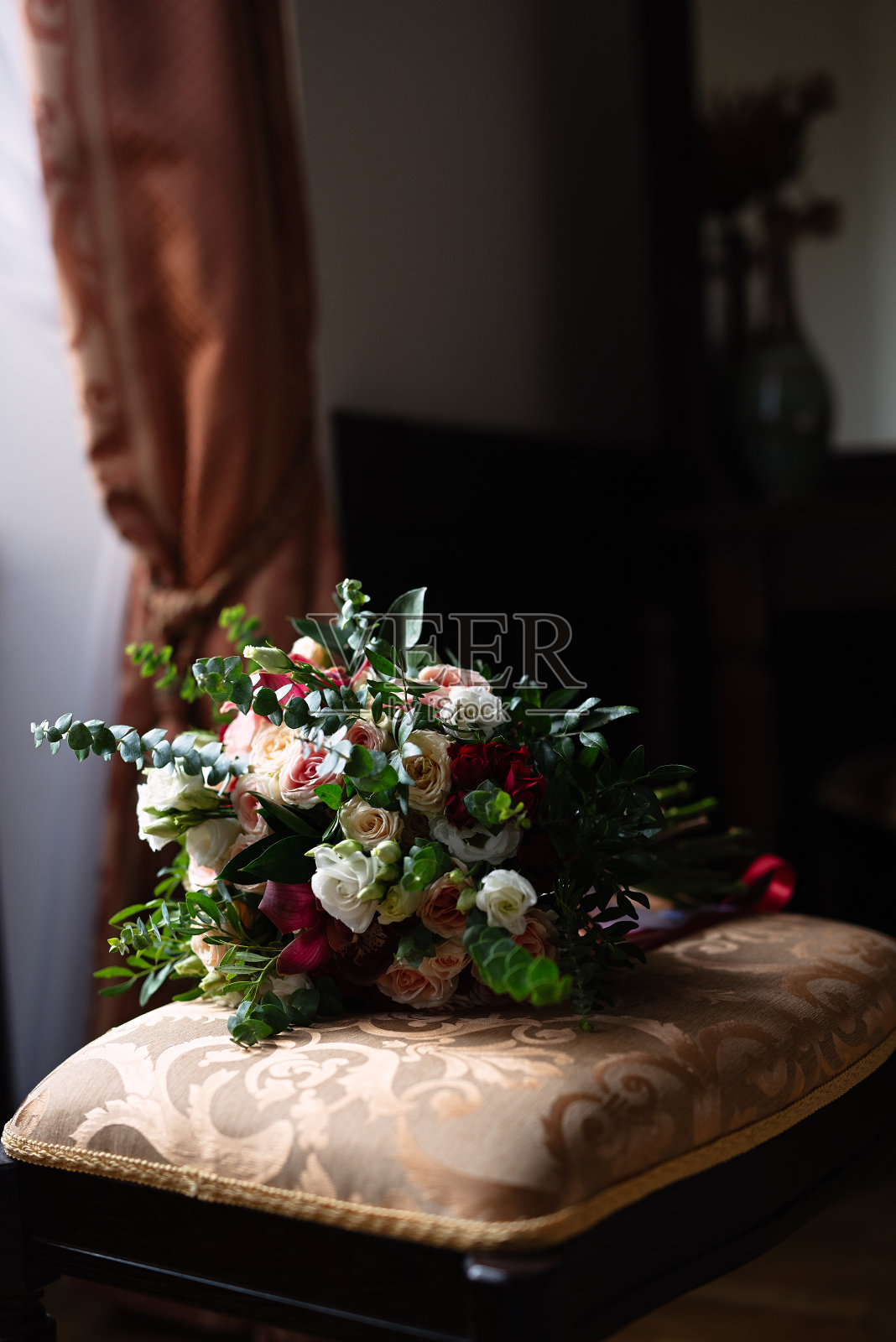 柔软的椅子上放着一大束花，昏暗的灯光，一张昏暗的照片，新娘的花束照片摄影图片