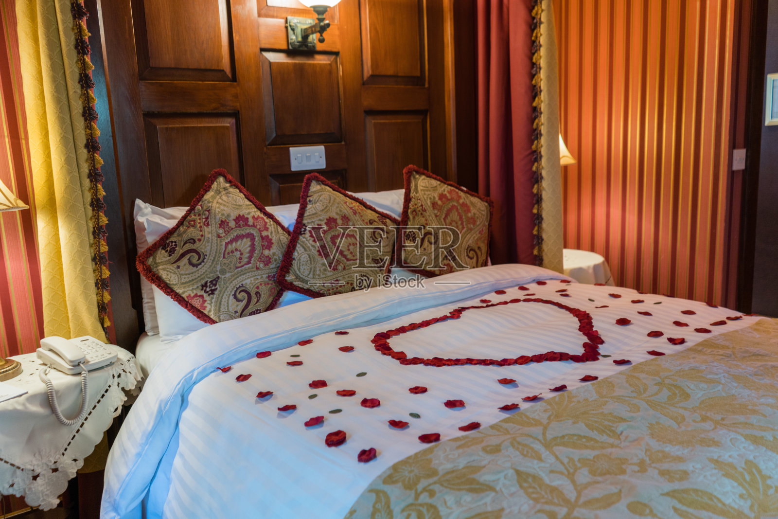 浪漫的酒店房间，床上有玫瑰花瓣，四柱床适合婚礼或情人节照片摄影图片
