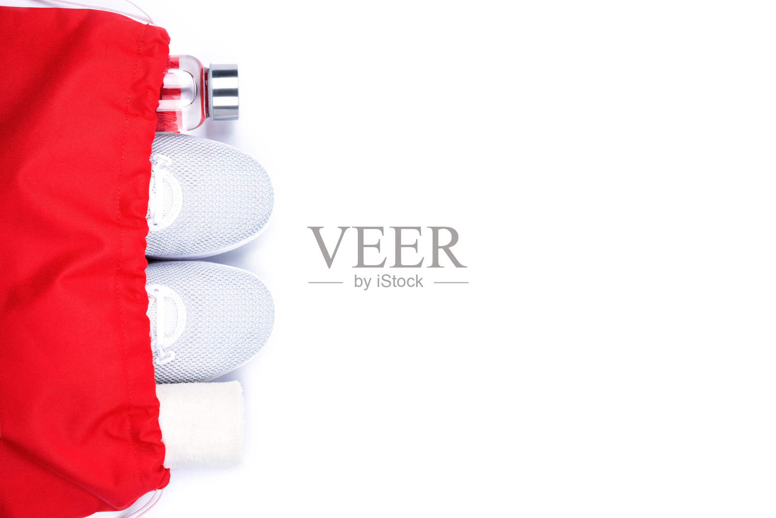白色运动鞋，玻璃水瓶和毛巾在红色运动包孤立在白色背景。照片摄影图片