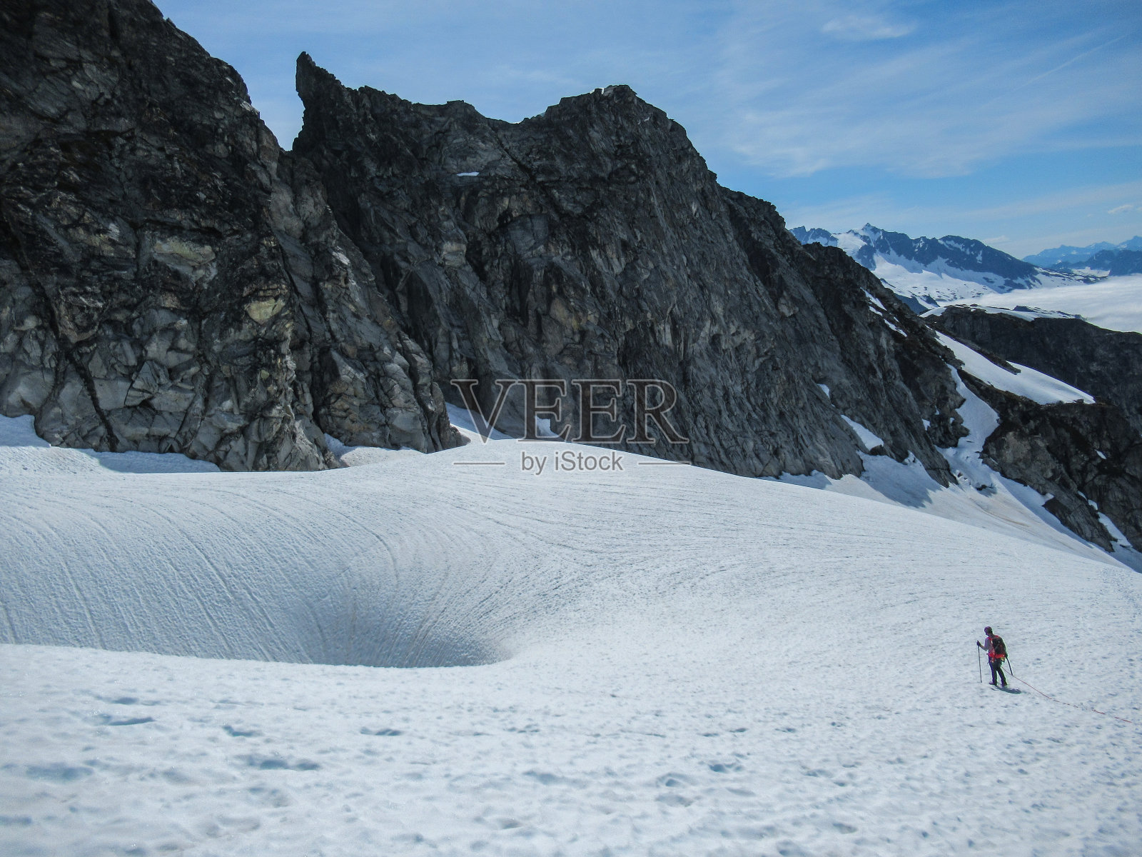 登山者接近山上冰川上的天坑照片摄影图片