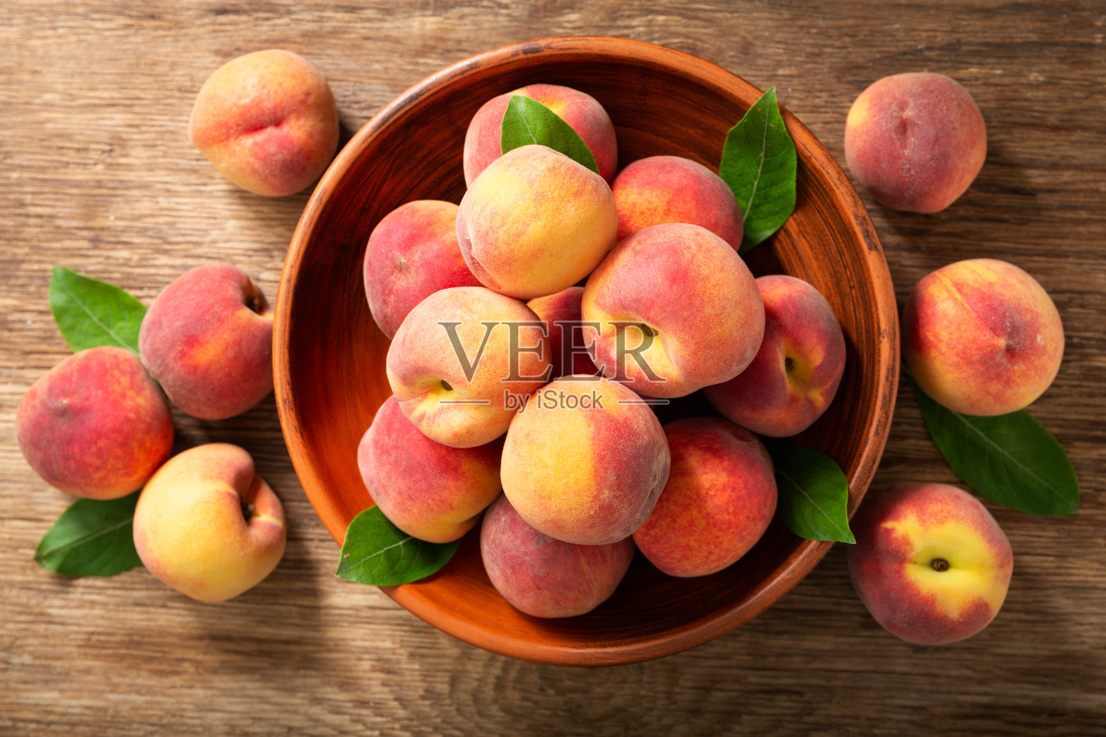 新鲜成熟的桃子与叶片在碗中，俯视图照片摄影图片