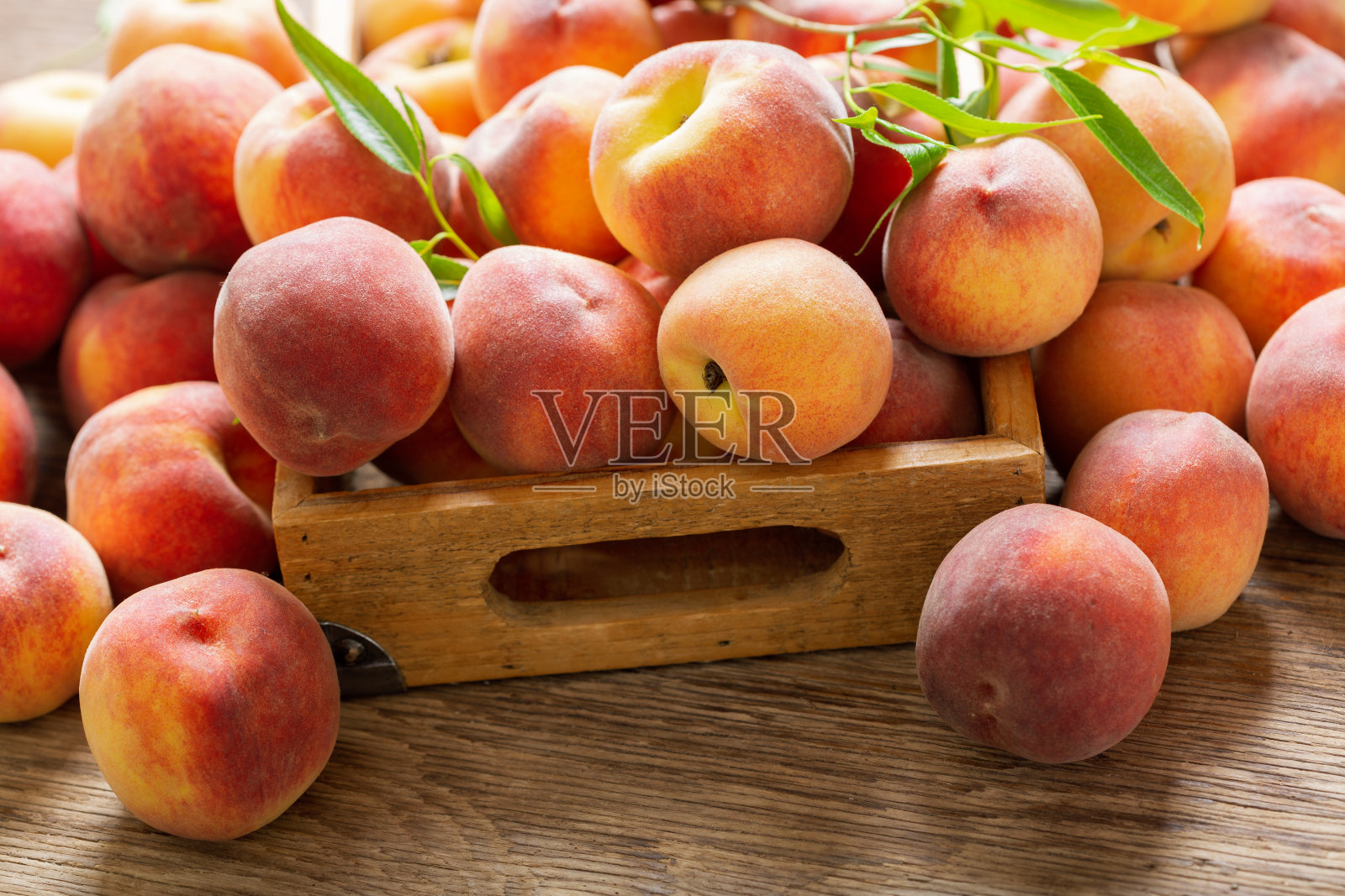 新鲜成熟的桃子和叶片装在木盒子里照片摄影图片