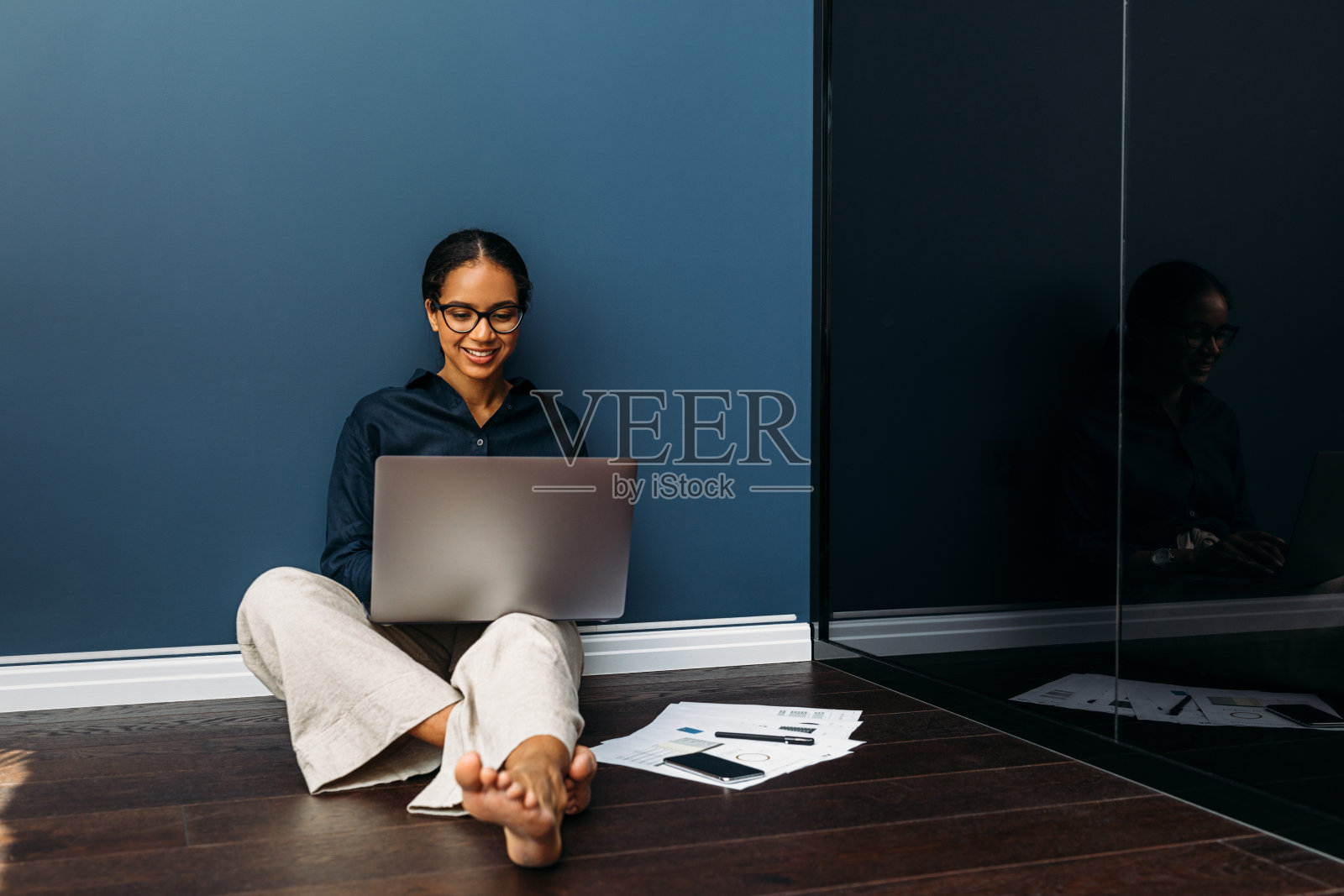 微笑的企业家坐在家里的地板上，腿上放着一台笔记本电脑照片摄影图片