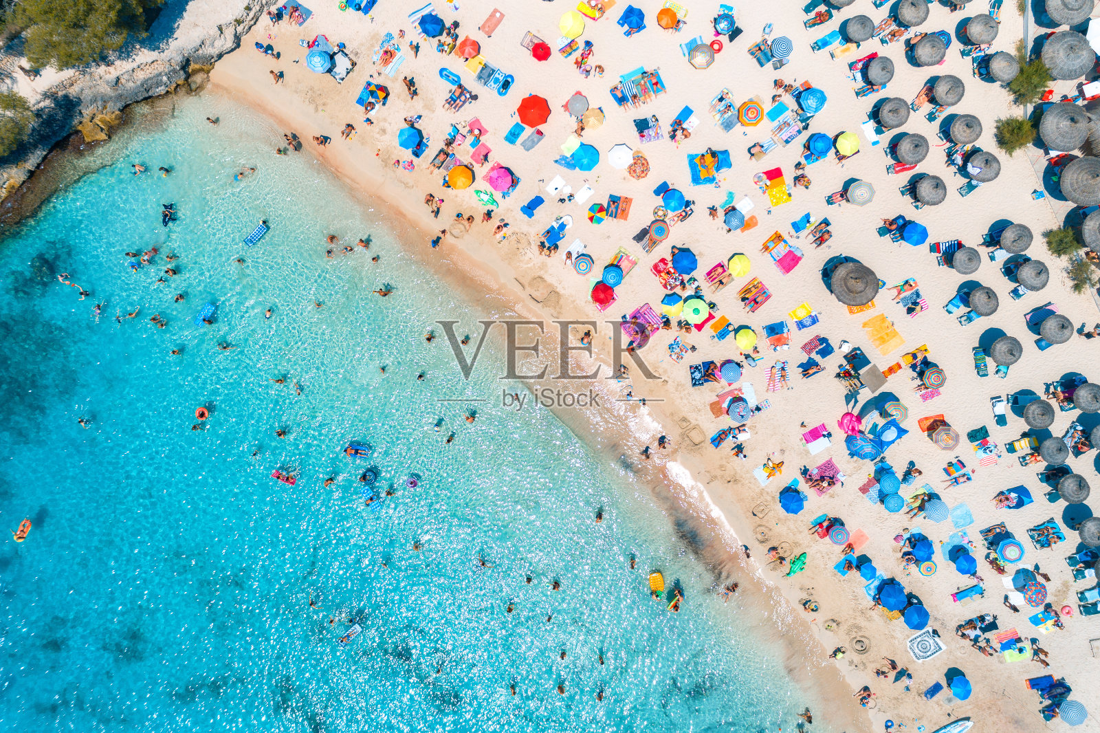 夏日日落时分，沙滩上的人在透明的蓝色海水中游泳。在西班牙巴利阿里群岛的马略卡岛旅游。从以上观点。景观照片摄影图片