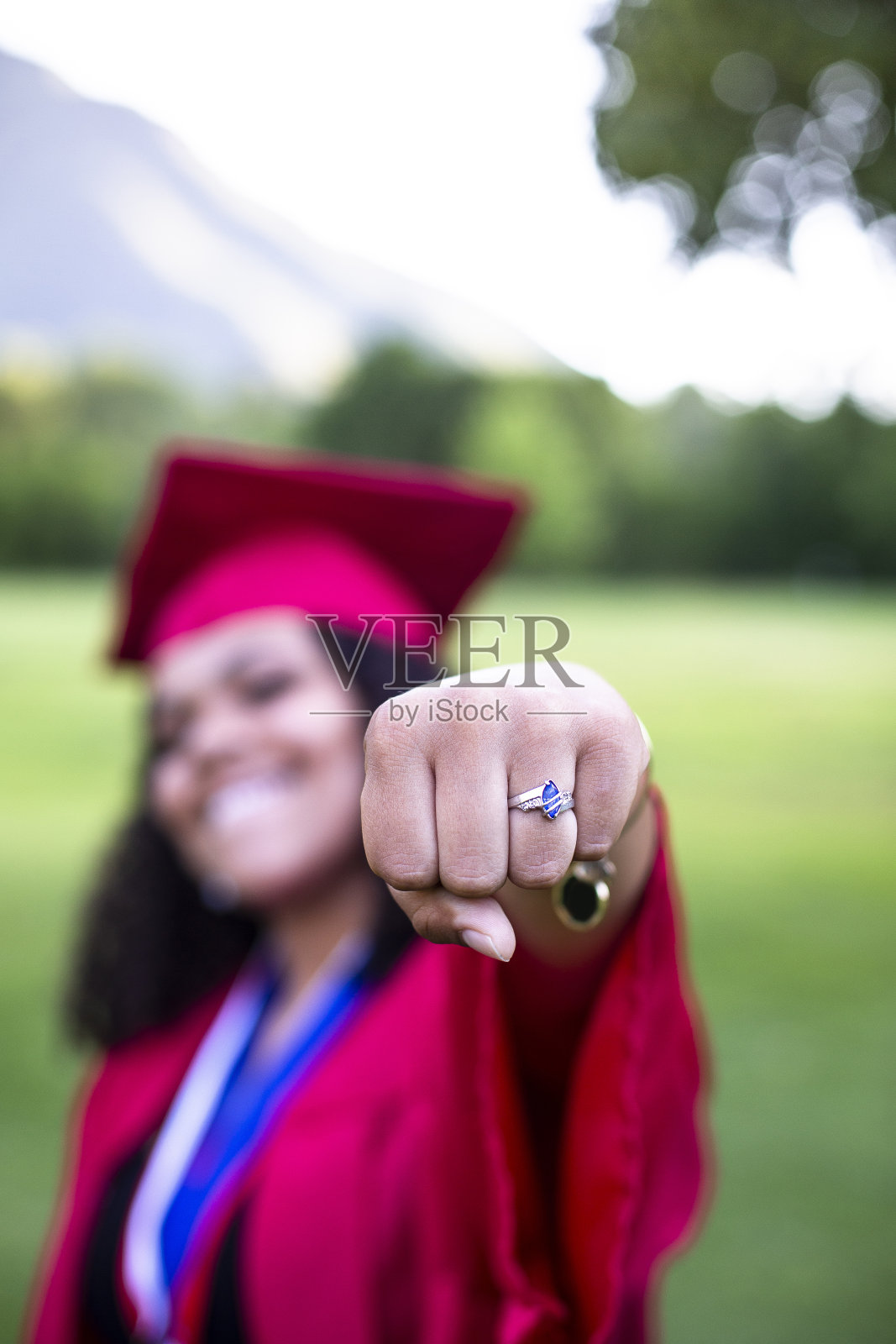多民族妇女在她的毕业帽和长袍给予拳头泵照片摄影图片