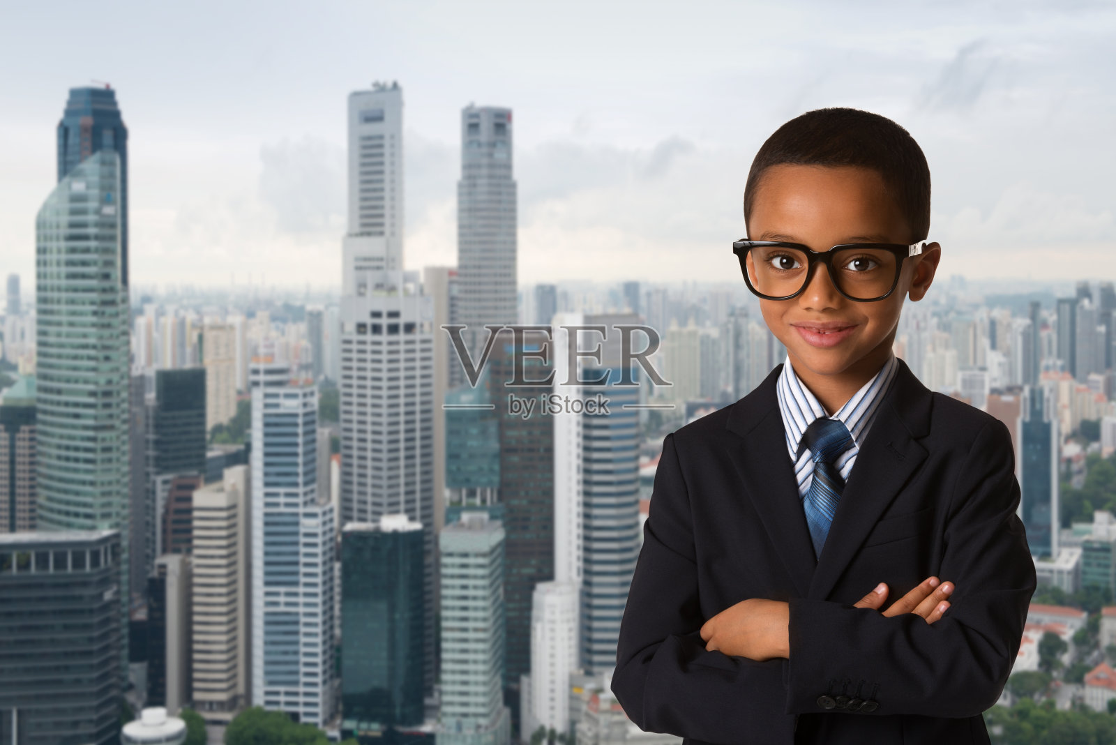 童年和人们的概念——非洲裔美国小男孩戴着眼镜，穿着西装，背景是城市。冷静自信的微笑姿势。照片摄影图片