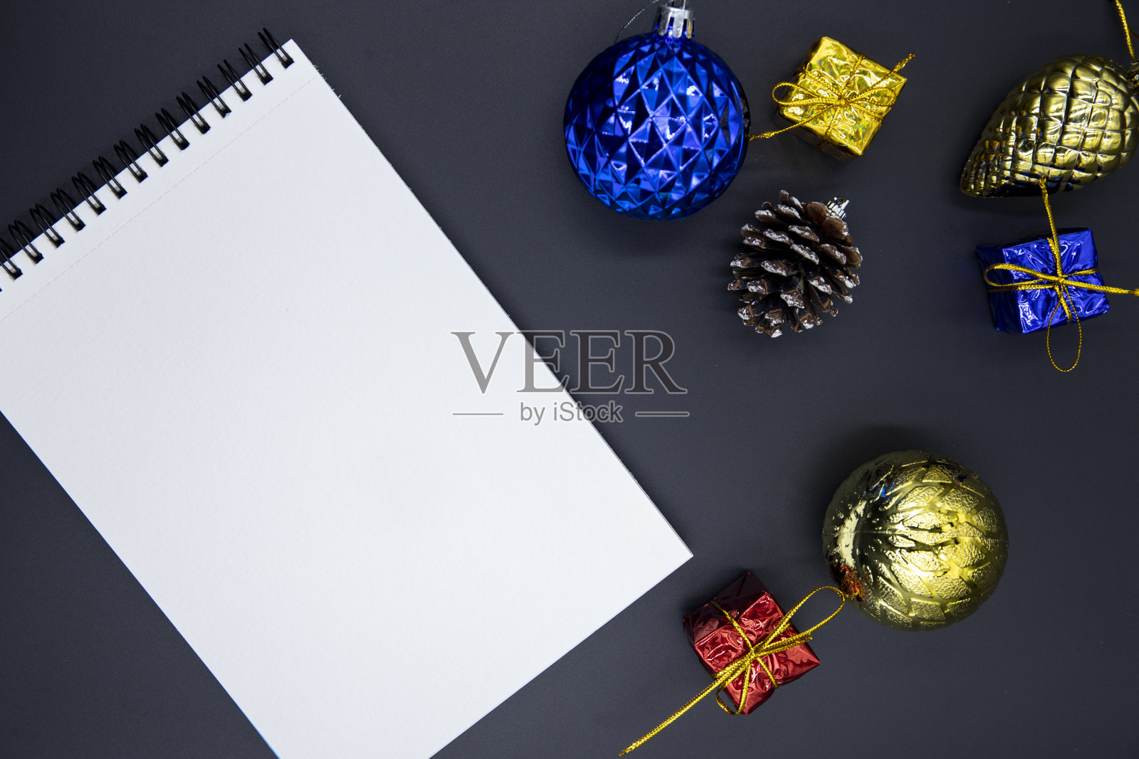 白色的记事本在黑色的桌子与圣诞树装饰。冬季假期模型的标志，字母或草图。照片摄影图片