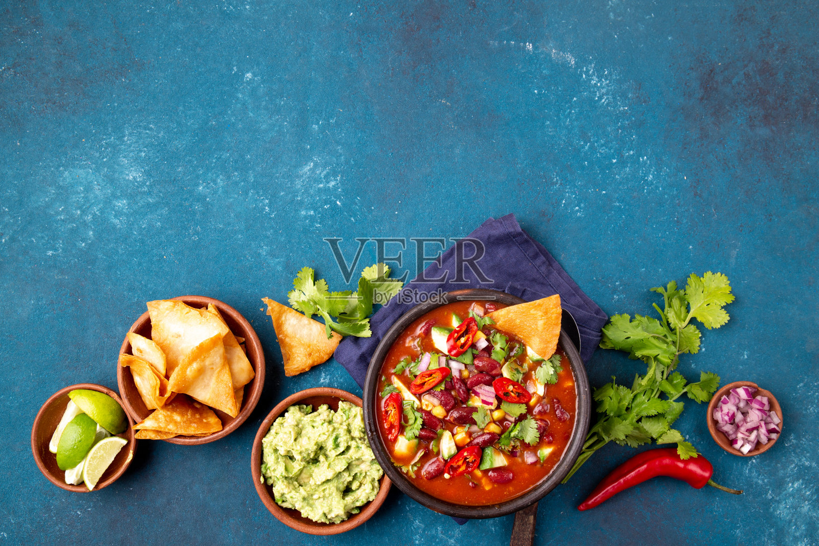 墨西哥食物概念背景与辣椒黑豆汤，鳄梨色拉酱和玉米片。俯视图照片摄影图片