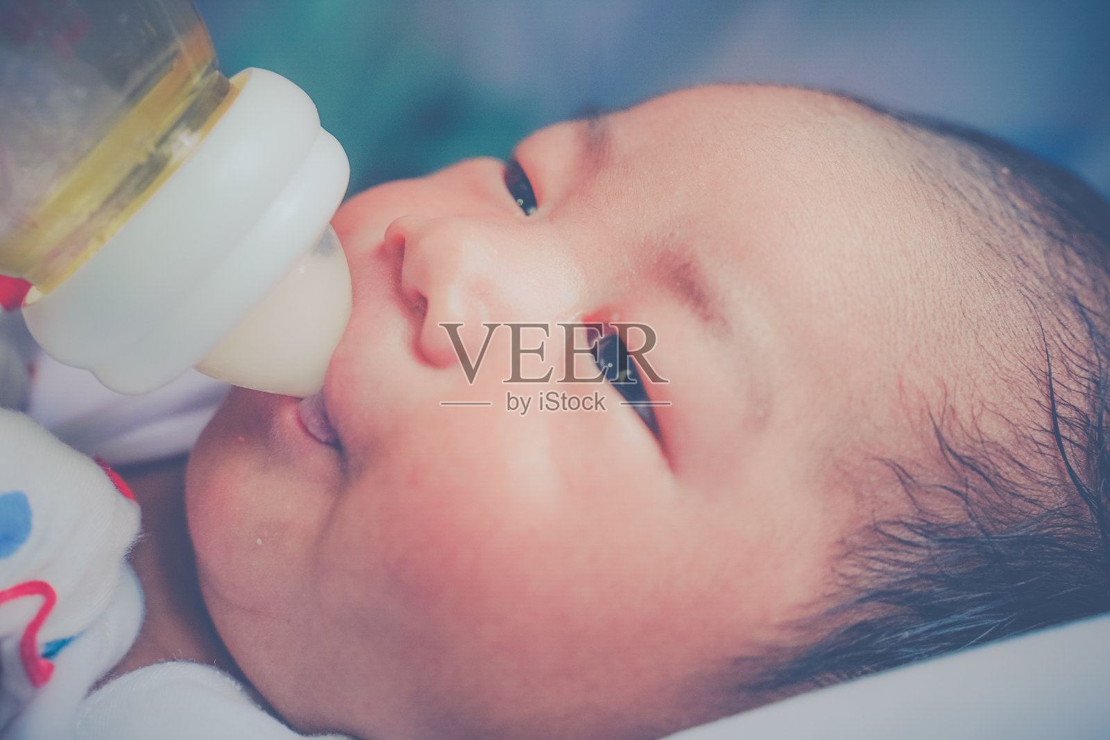 这个小男孩自己拿着奶瓶喝着奶水。新生儿母乳喂养的概念。照片摄影图片