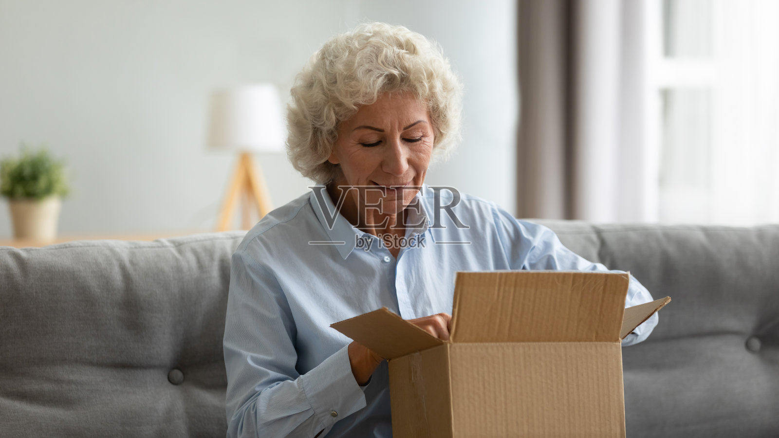 快乐的65岁老妇人打开快递包裹照片摄影图片