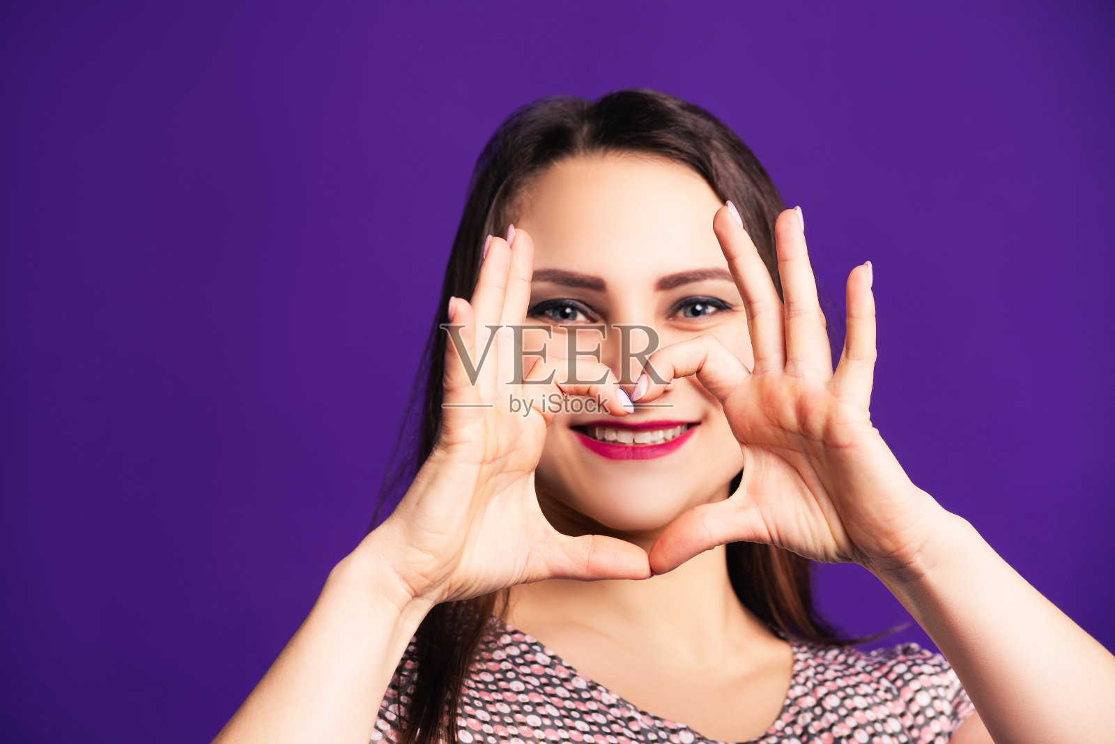快乐的女人显示心形标志在紫色的背景照片摄影图片