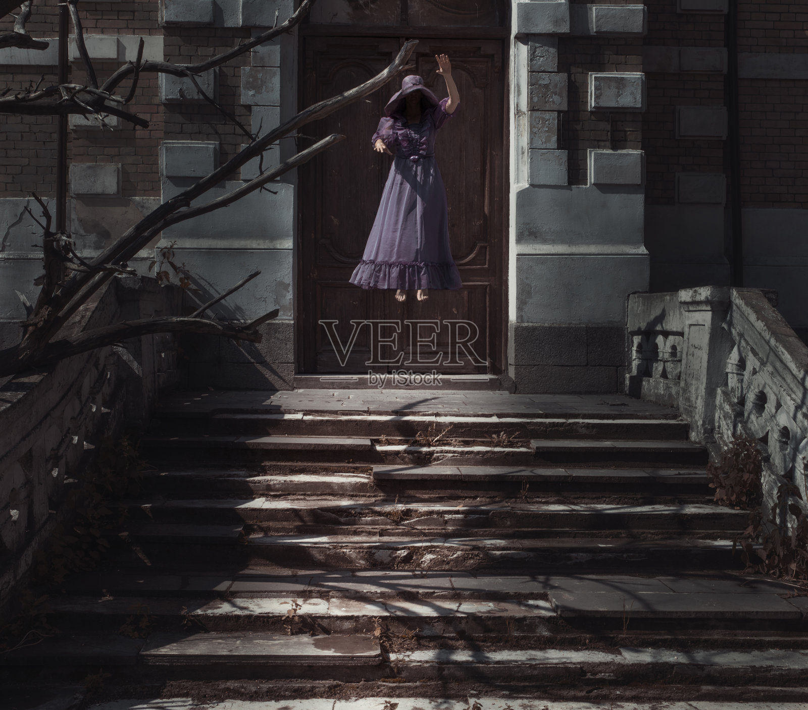 一个女人在废弃的房子前在空中翱翔。女鬼的恐怖场景。照片摄影图片