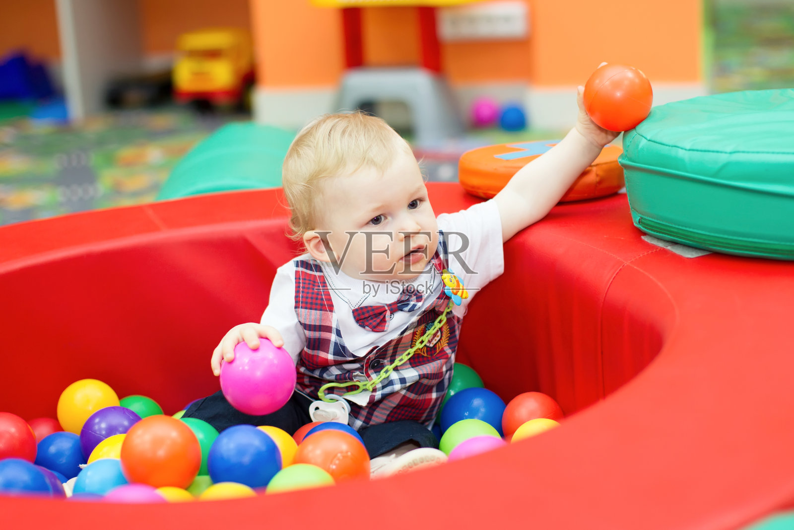 一个一岁的小男孩在一个装着塑料球的篮子里照片摄影图片
