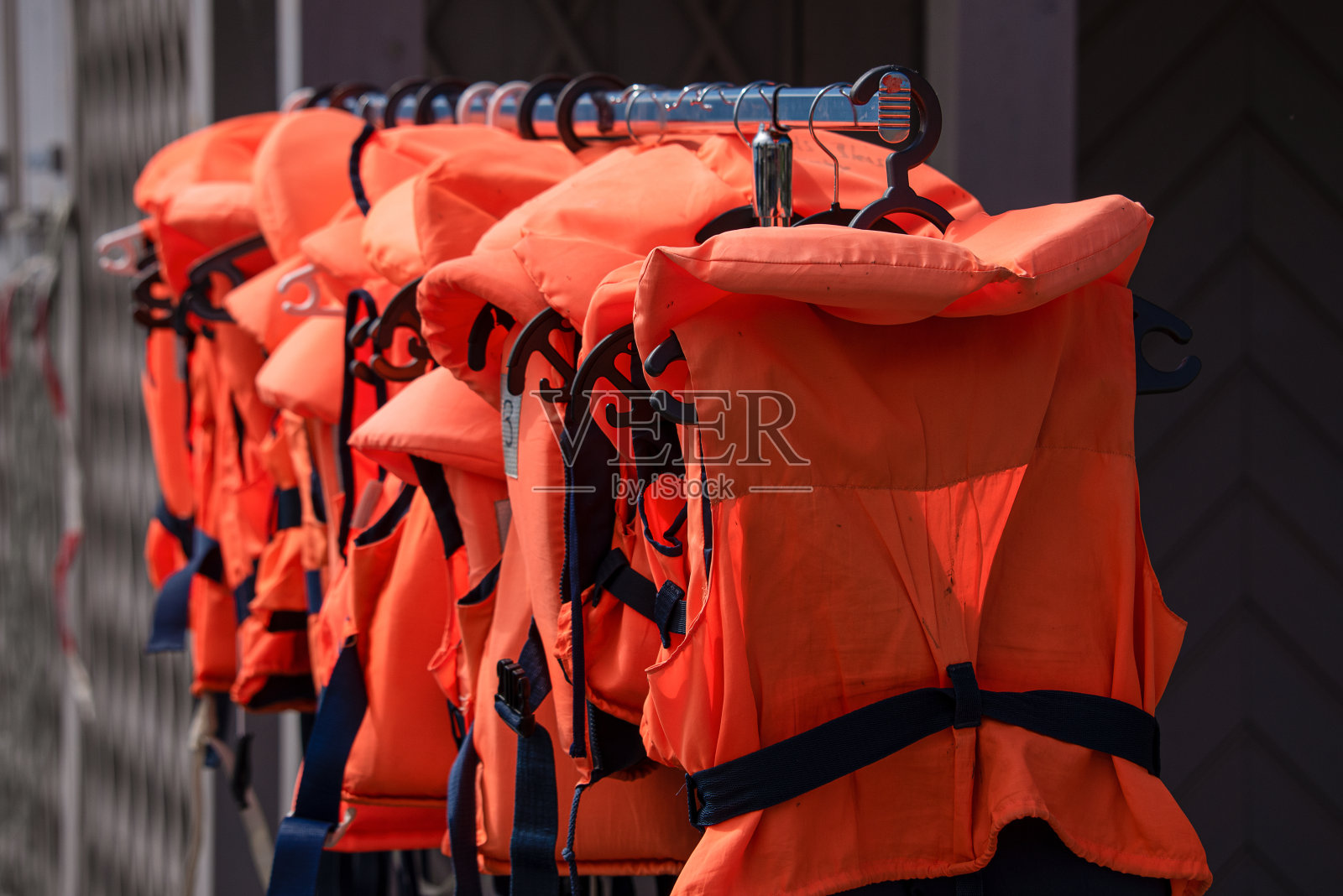橙色和黑色的救生衣排成一排。照片摄影图片