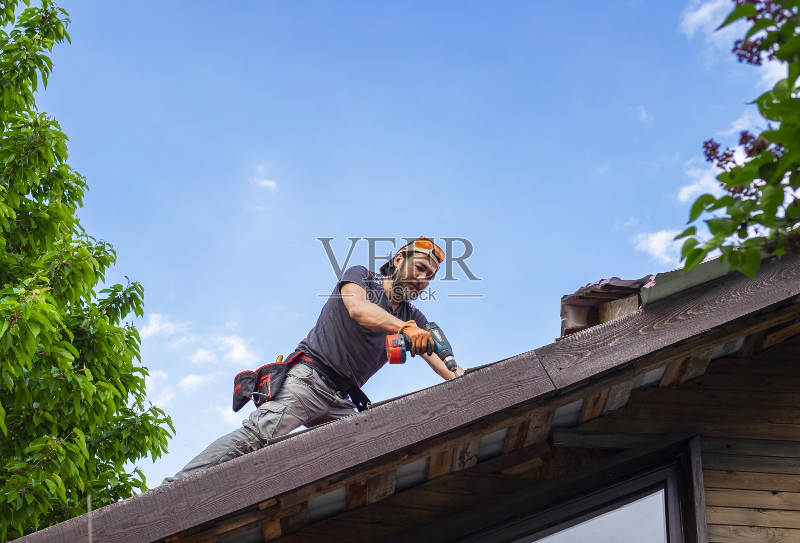 用电动螺丝刀在屋顶上工作的人照片摄影图片