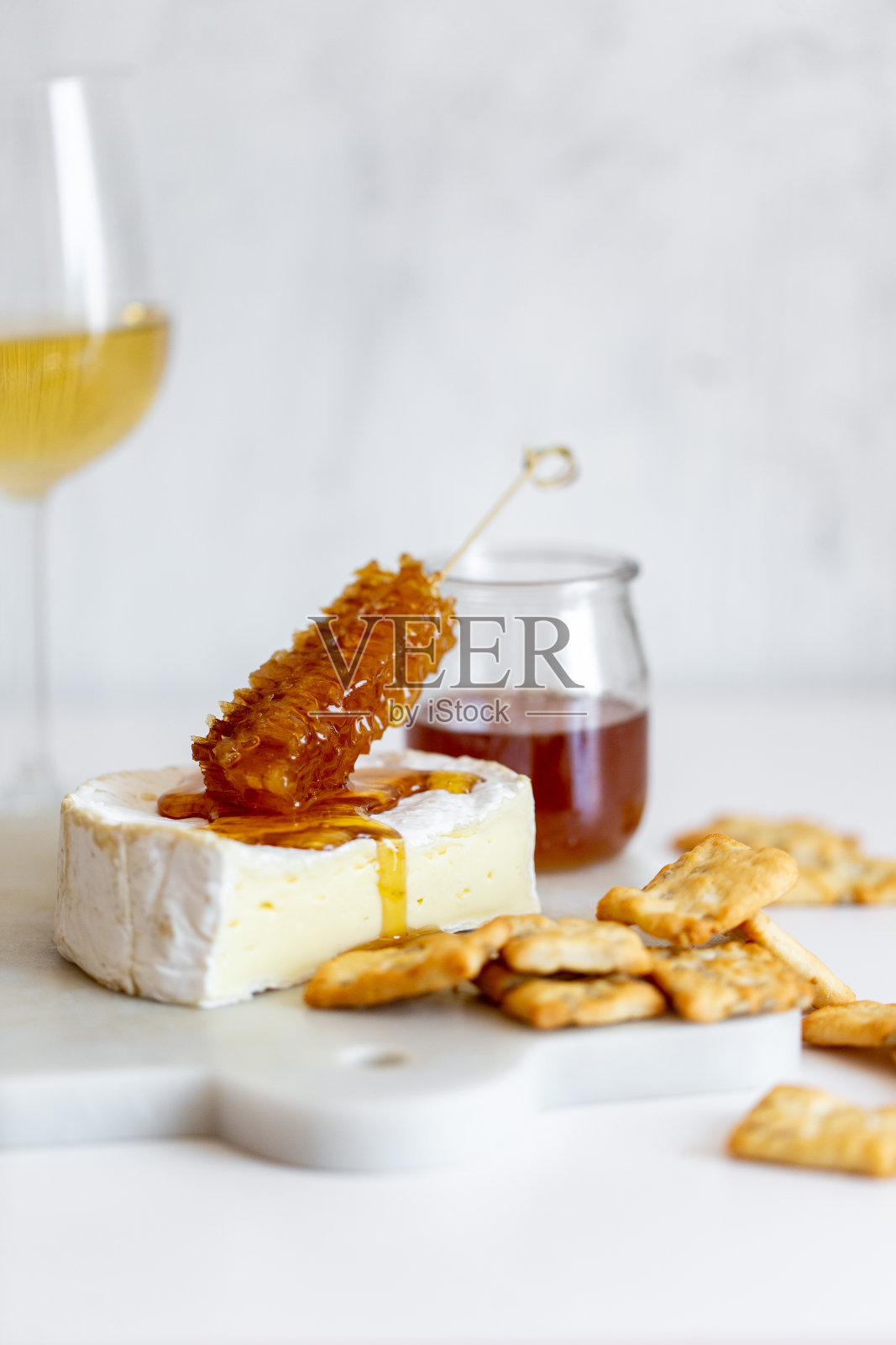 卡芒贝尔奶酪，白葡萄酒蜂蜜和小吃在白色大理石的背景照片摄影图片