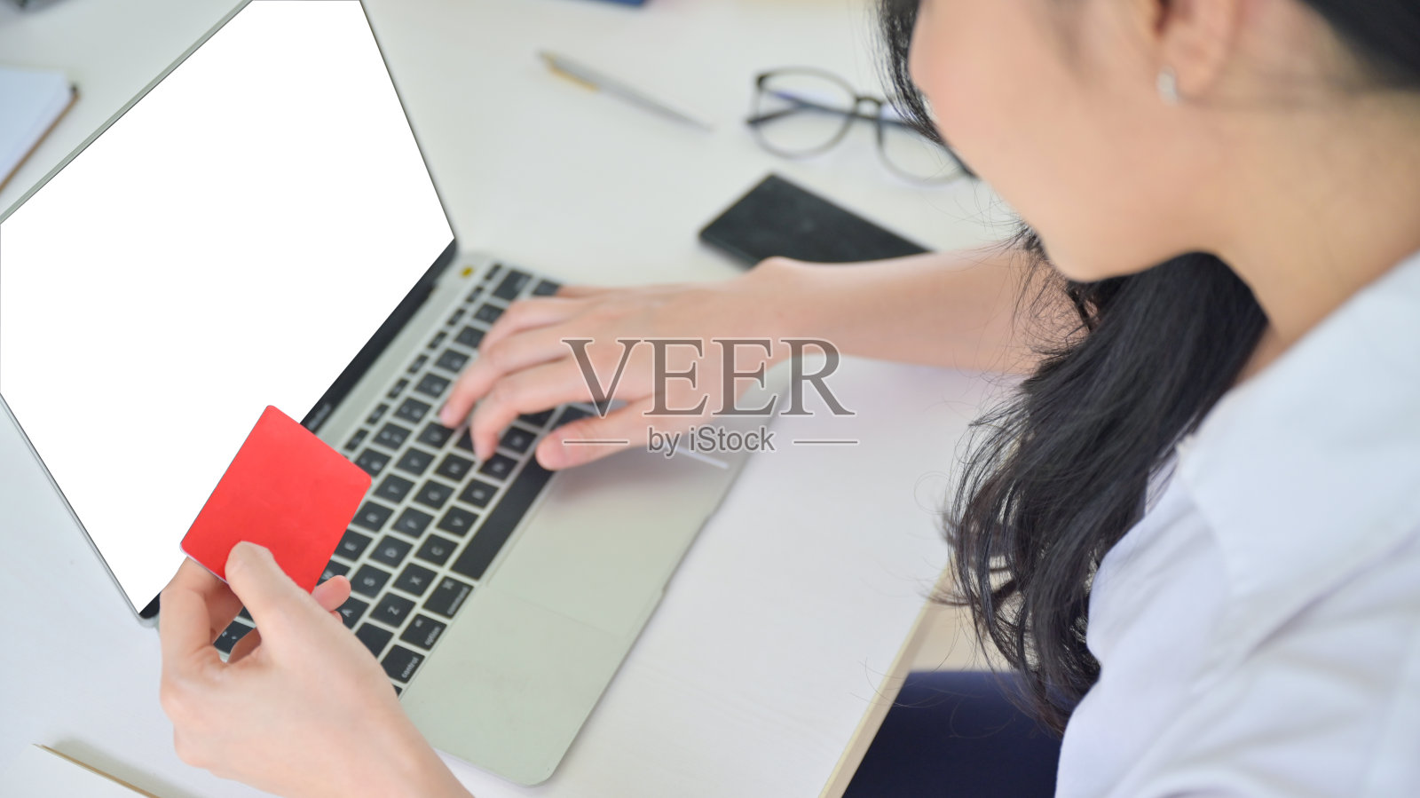 女人手里拿着信用卡。她正在用一台笔记本电脑支付这项服务的费用。照片摄影图片