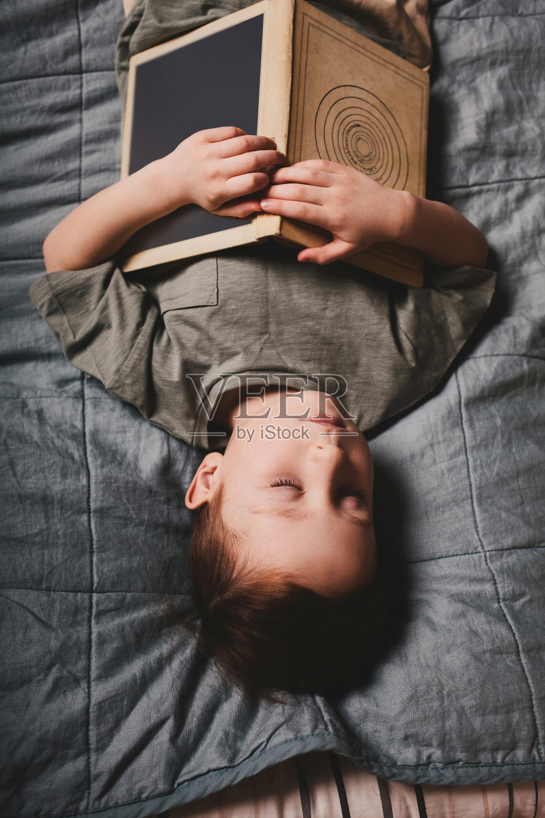 男孩躲在一本书后面睡着了。家庭教育，爱好，阅读。照片摄影图片