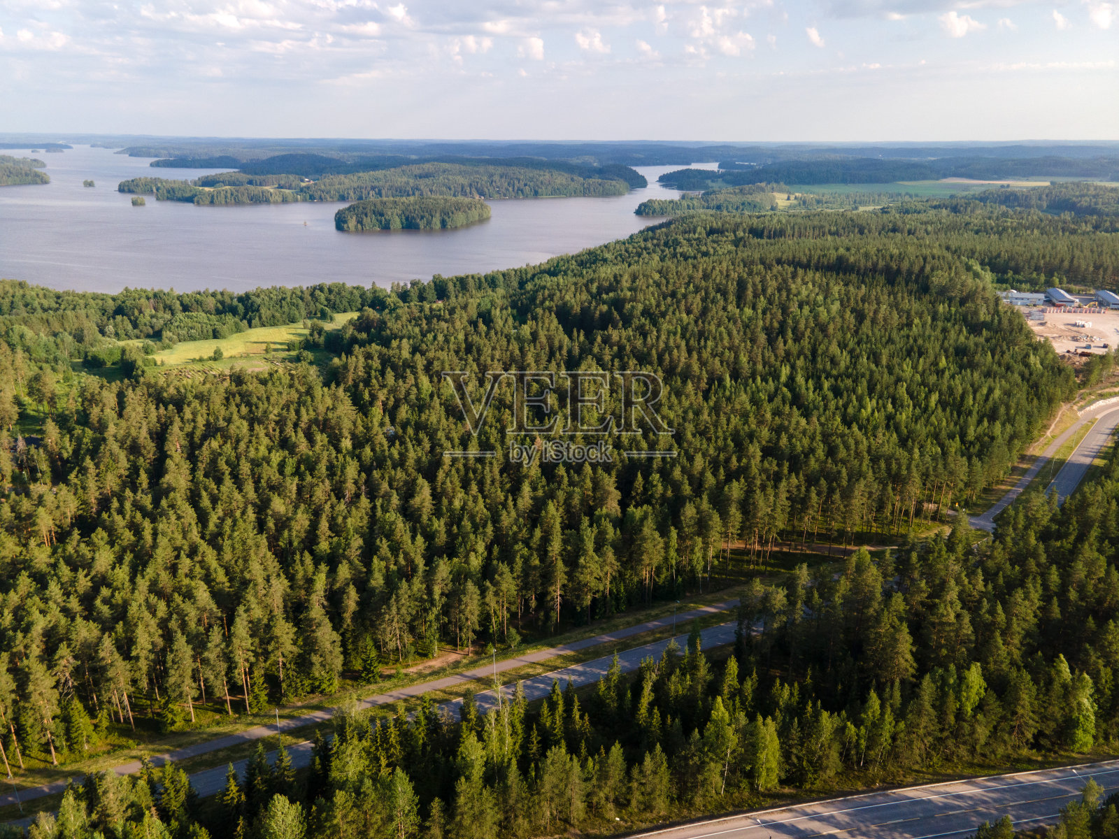 鸟瞰图的蓝色湖泊与阳光森林在芬兰拉普兰。照片摄影图片