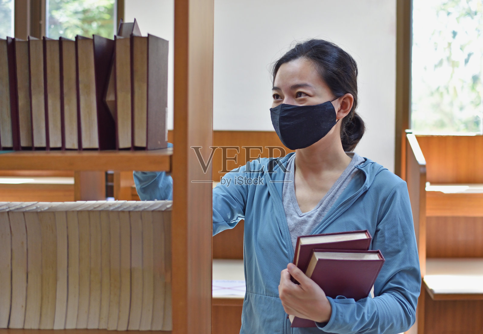 一个戴医用口罩的女人在图书馆找书照片摄影图片