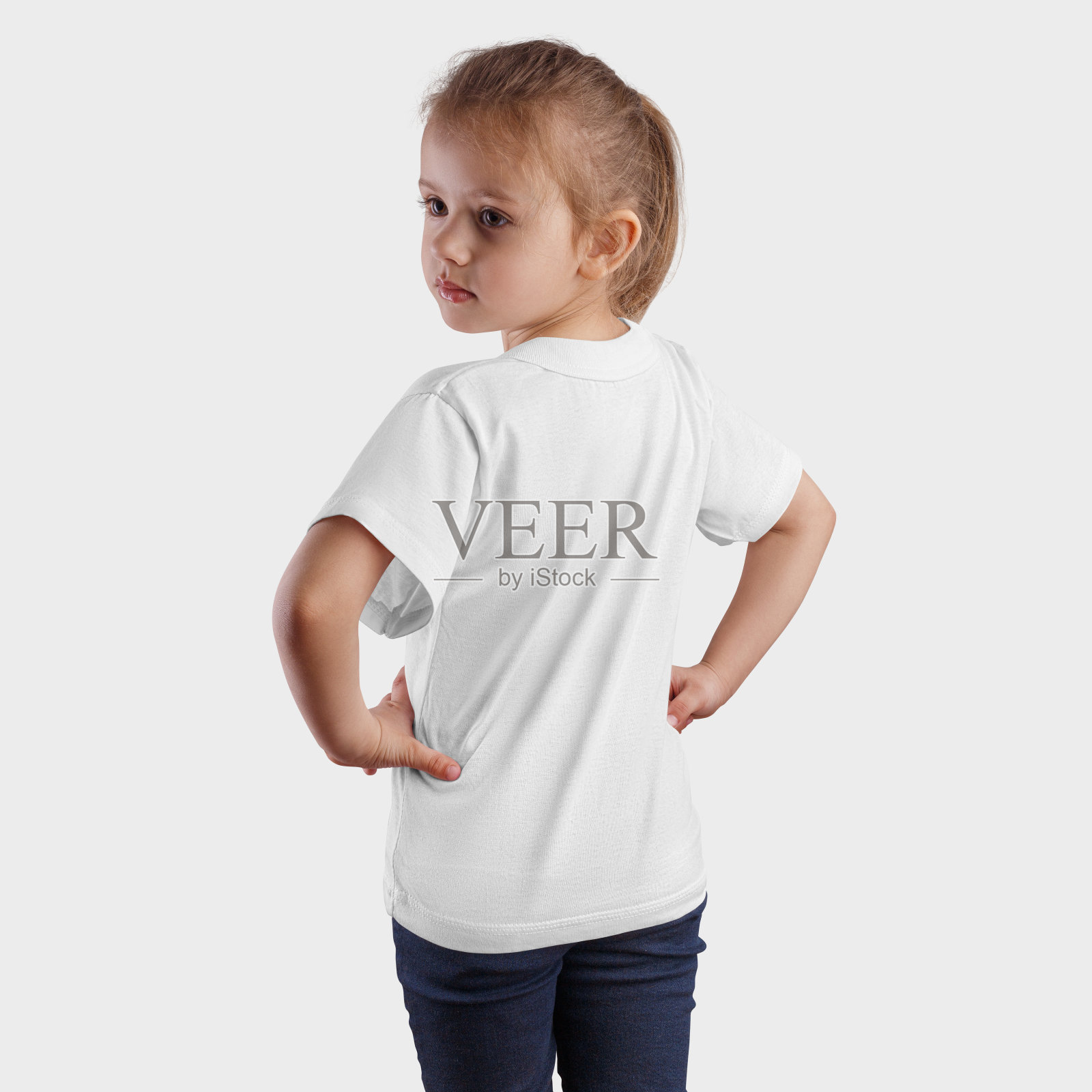在一个站着的漂亮女孩的白色t恤的模型，回头，时尚的婴儿衣服的设计和模式的介绍。照片摄影图片