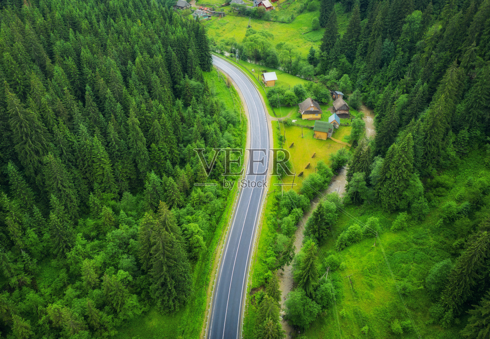 鸟瞰图的道路在美丽的绿色森林日落在夏天。丰富多彩的风景有马路，松树。Carpatian山脉。俯视图从高速公路的无人机。从以上观点。旅行在乌克兰照片摄影图片