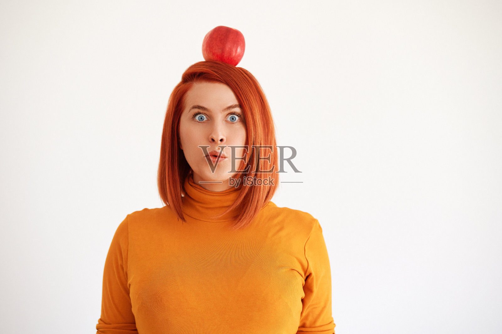 红苹果放在红头发的头上照片摄影图片