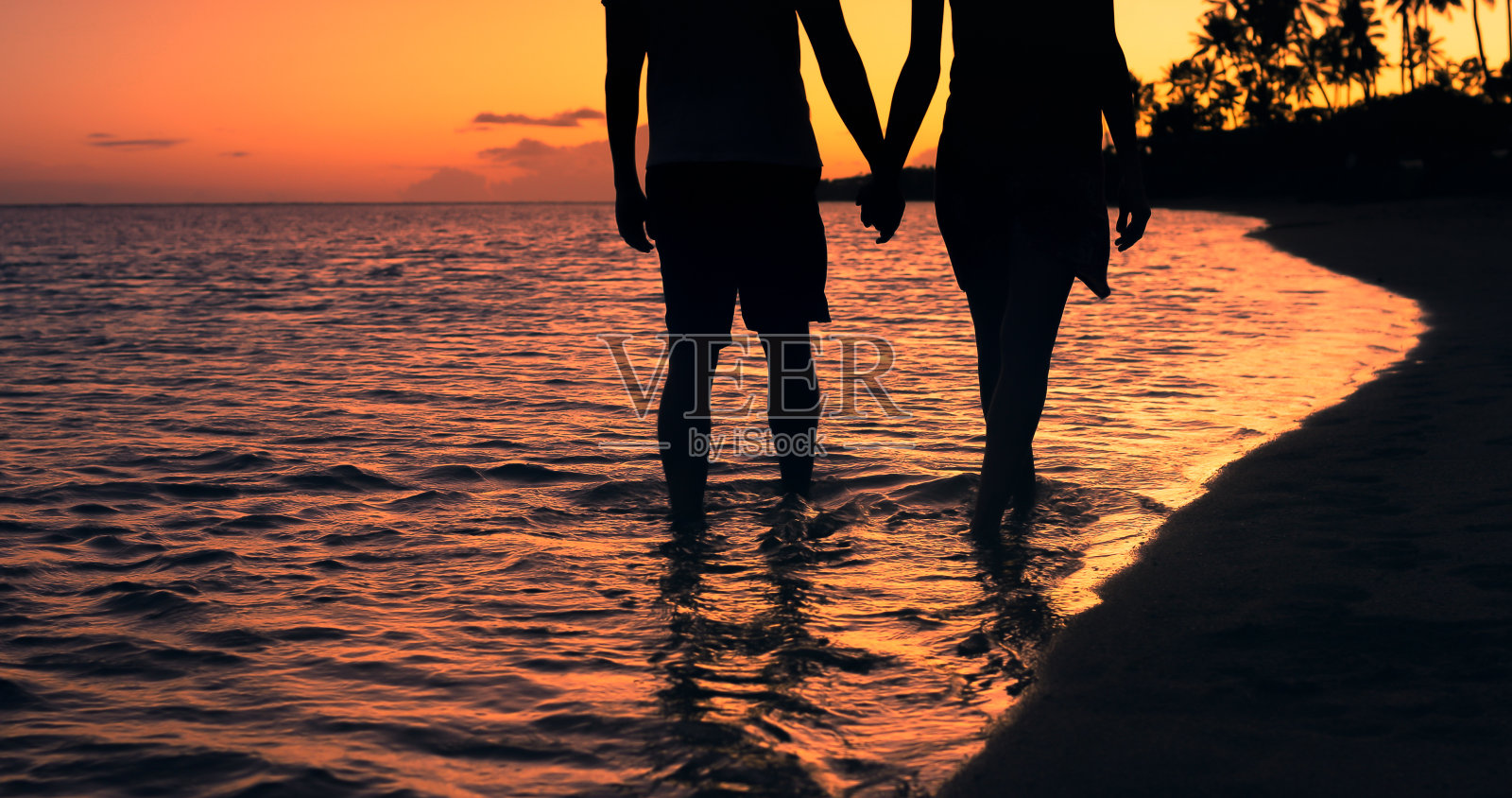男人和女人手牵着手走在热带岛屿的海滩上。照片摄影图片