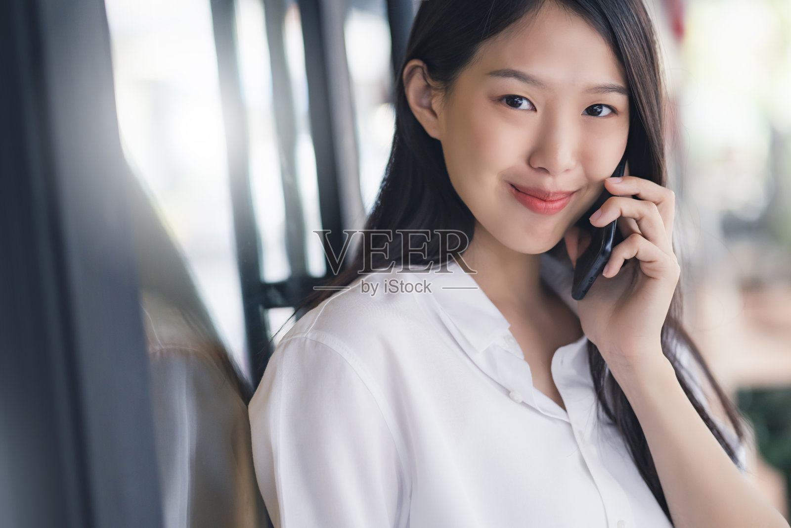 聪明活跃的亚洲女商人站在智能手机的店面背景下自信和快乐地与客户交谈照片摄影图片