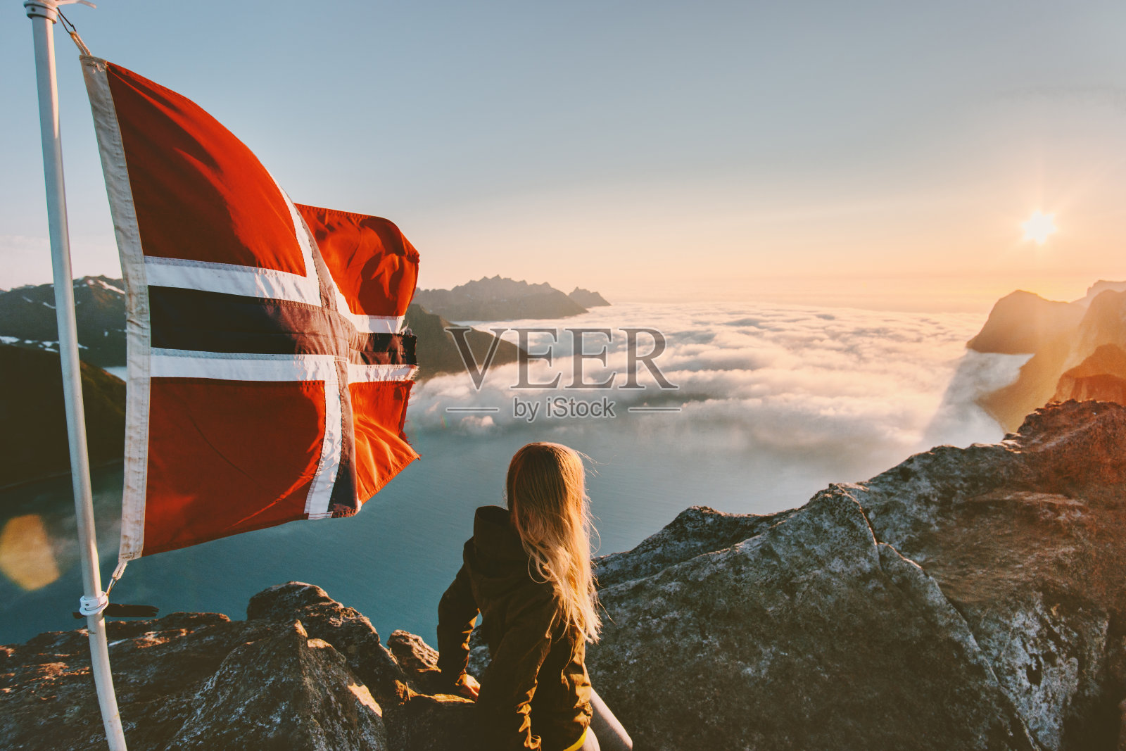 女人享受日落山景和挪威国旗上的顶级旅行生活方式，徒步旅行，冒险度假户外照片摄影图片