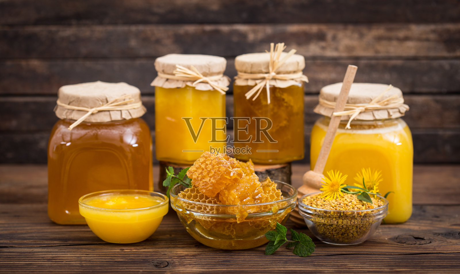 在碗和罐子里放新鲜的蜂蜜，还有蜂房和蜂花粉照片摄影图片