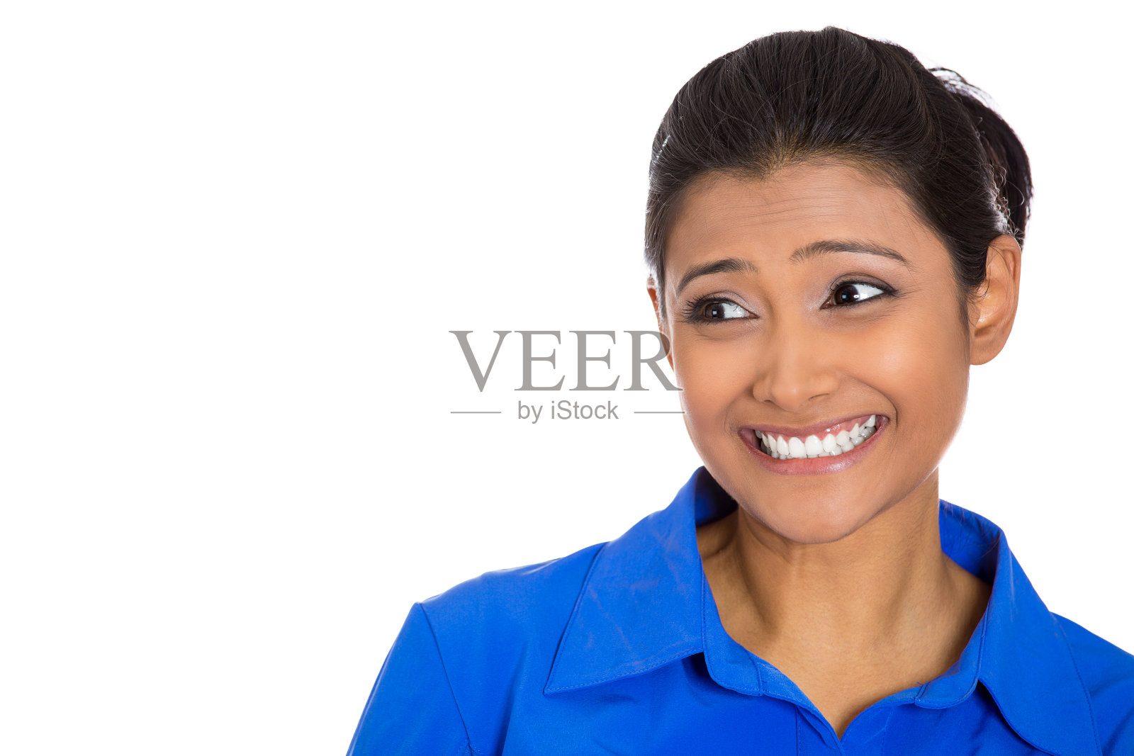 一个微笑的快乐的年轻女子的肖像穿着蓝色的衬衫看向一边照片摄影图片