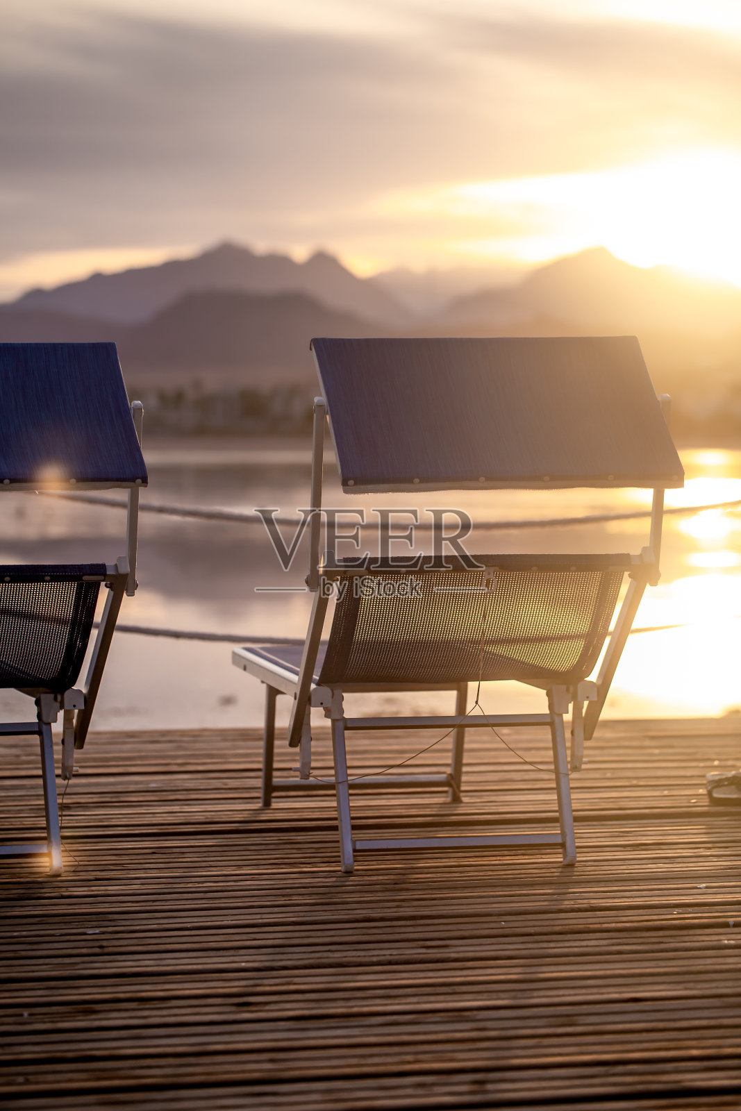日落时分，木制码头上的两把空椅子照片摄影图片