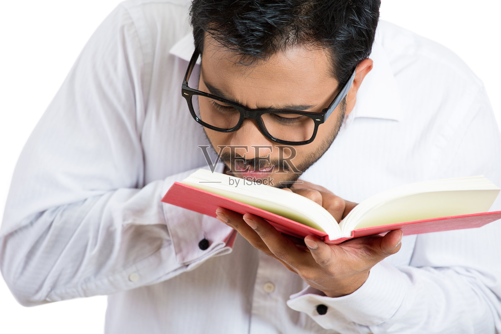 一个戴着眼镜的年轻书呆子的肖像，试图阅读书籍，但由于视力问题，很难看到文字照片摄影图片