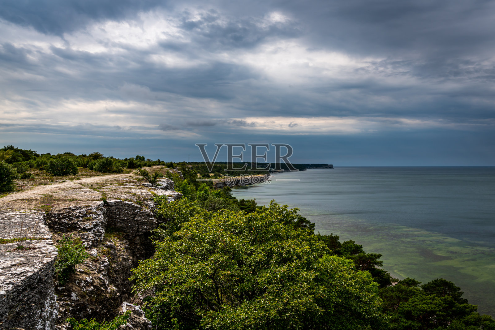 瑞典戈特兰岛的石灰岩悬崖的海岸线景观与雷云和地平线。照片摄影图片