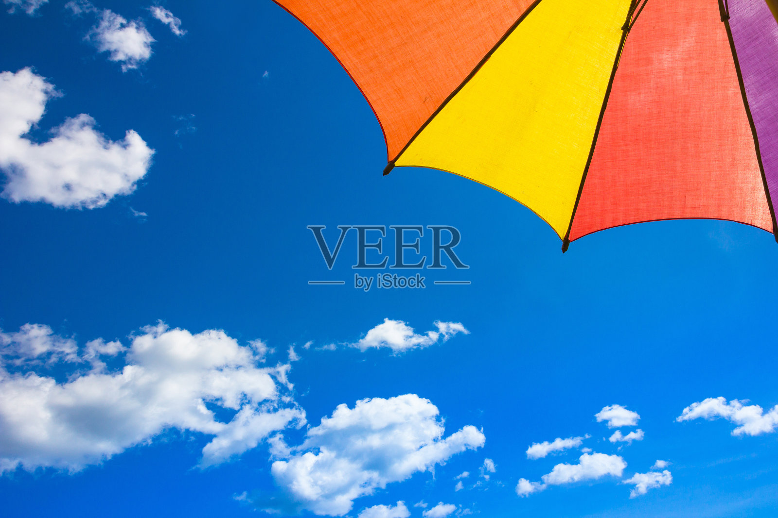 从遮阳伞下看，空间仿海滩彩色伞与蓝天和阳光。照片摄影图片