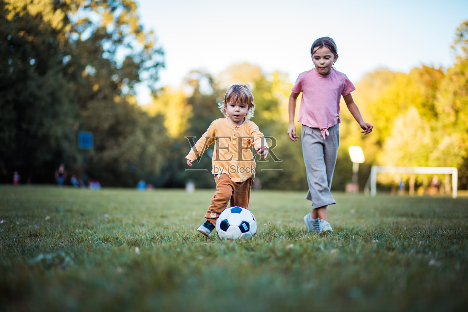 妹妹和弟弟在踢足球。照片摄影图片