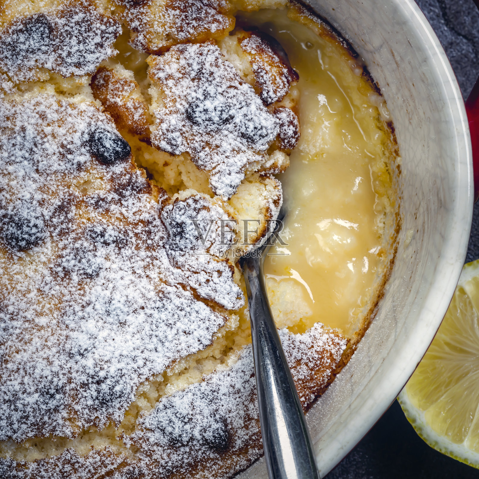 柠檬布丁，俯视图在烤盘与上菜勺。美味self-saucing甜点。照片摄影图片
