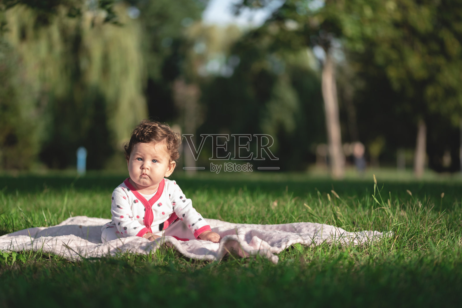 小女孩坐在公园的毯子上照片摄影图片