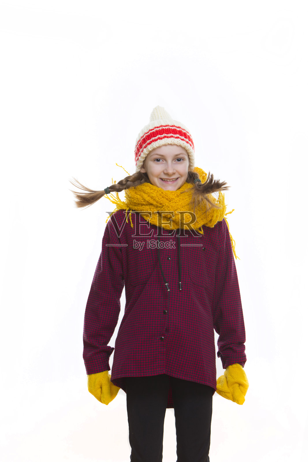 冬天孩子们的概念。积极跳跃的肖像积极的高加索女孩摆姿势在工作室的冬季服装对白色。垂直的形象定位照片摄影图片