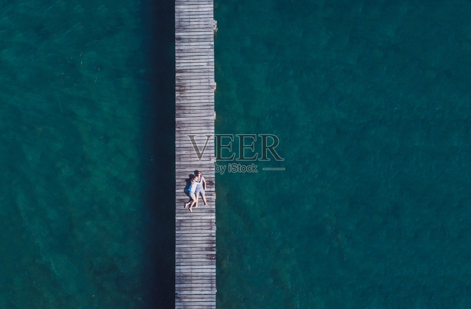 无人机鸟瞰蜜月浪漫夫妇躺在木码头，海滩度假照片摄影图片