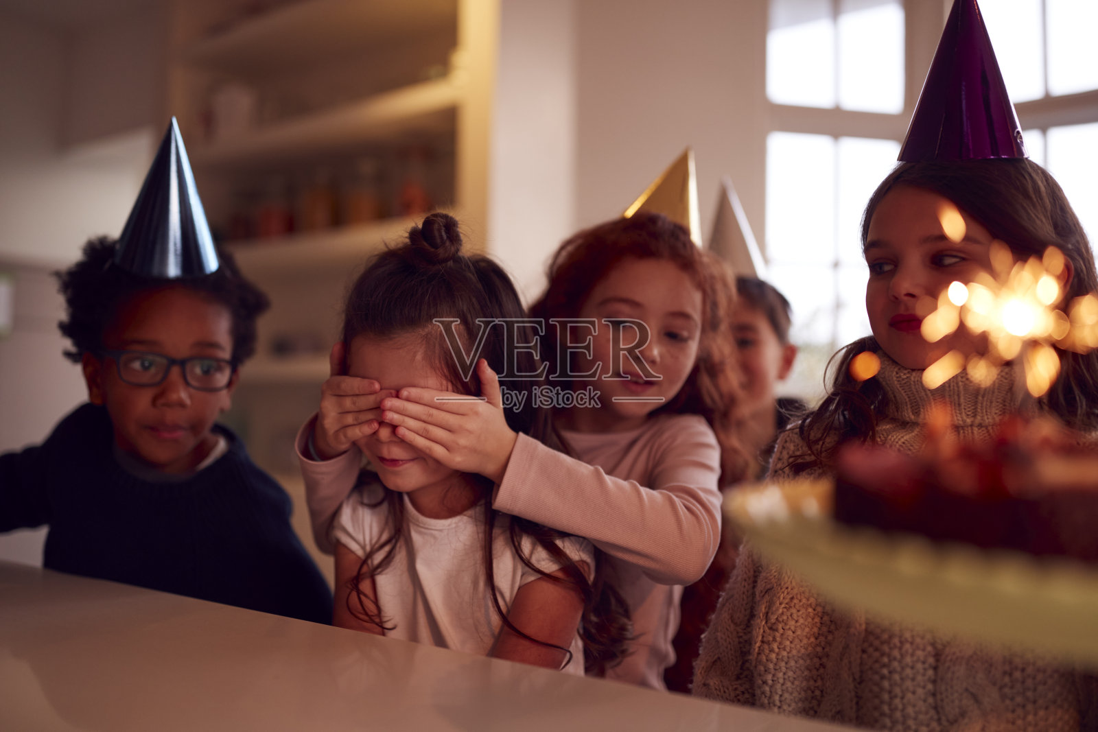 女孩和一群朋友在家里庆祝生日，收到了用烟花装饰的蛋糕照片摄影图片
