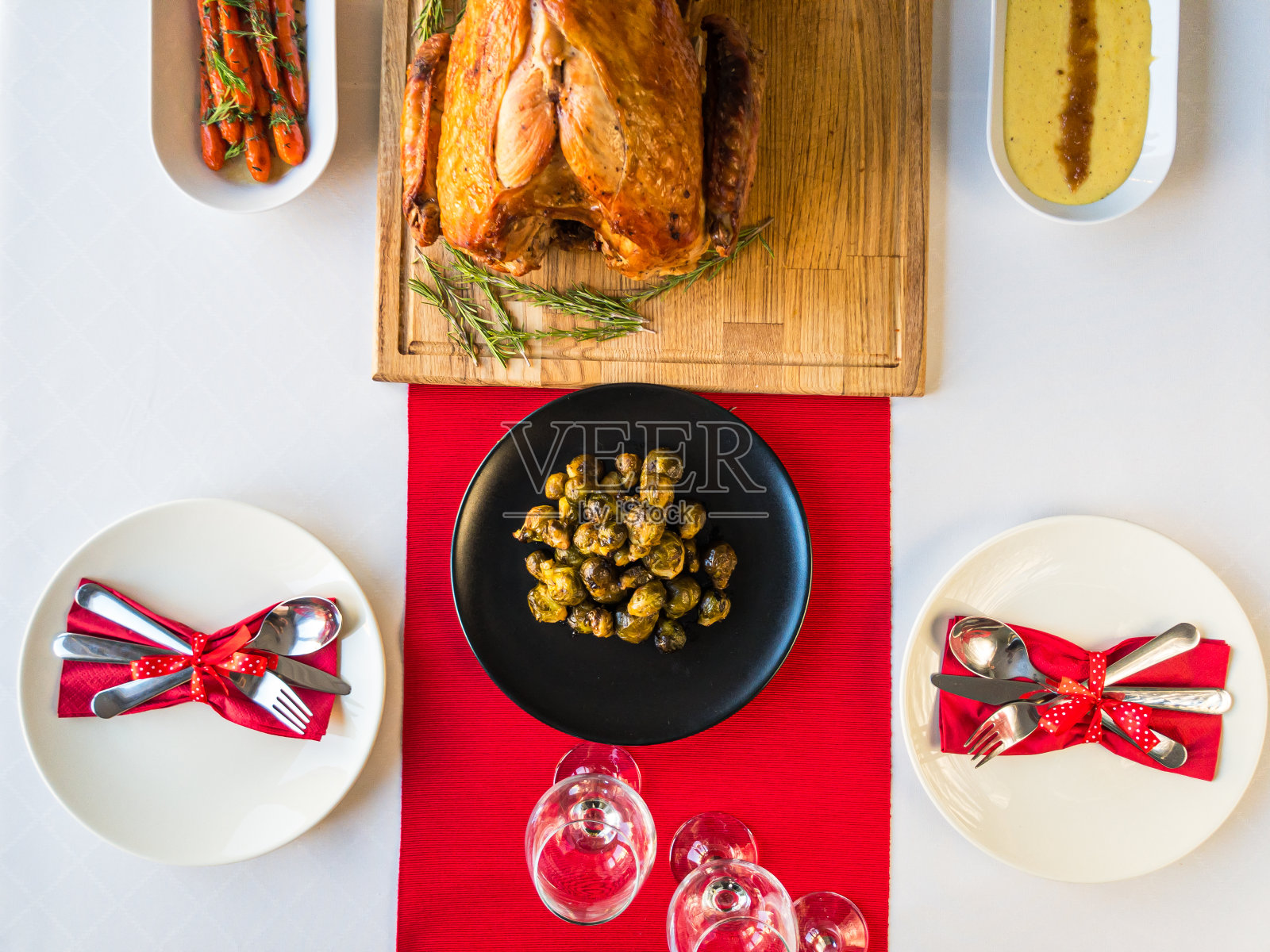 圣诞餐桌的概念是把整只烤火鸡放在木砧板上，配以甘蓝菜、釉面胡萝卜、土豆泥和餐具照片摄影图片