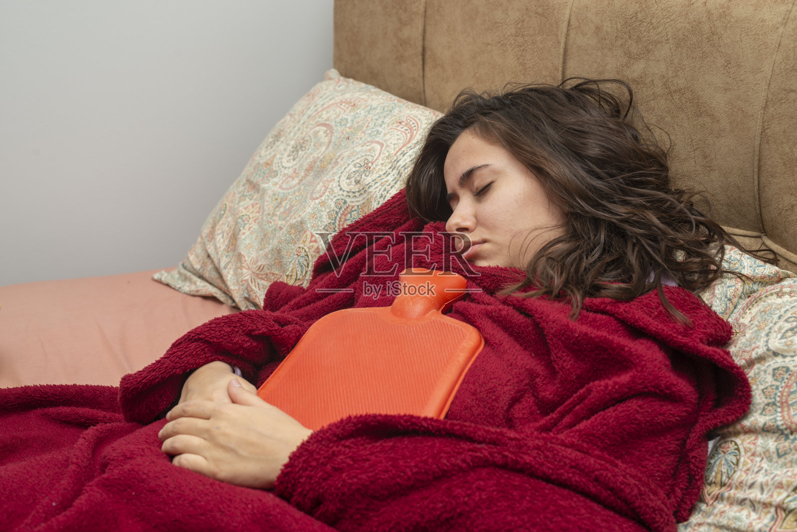 生病的年轻女子正在床上休息。Covid - 19居家隔离。照片摄影图片