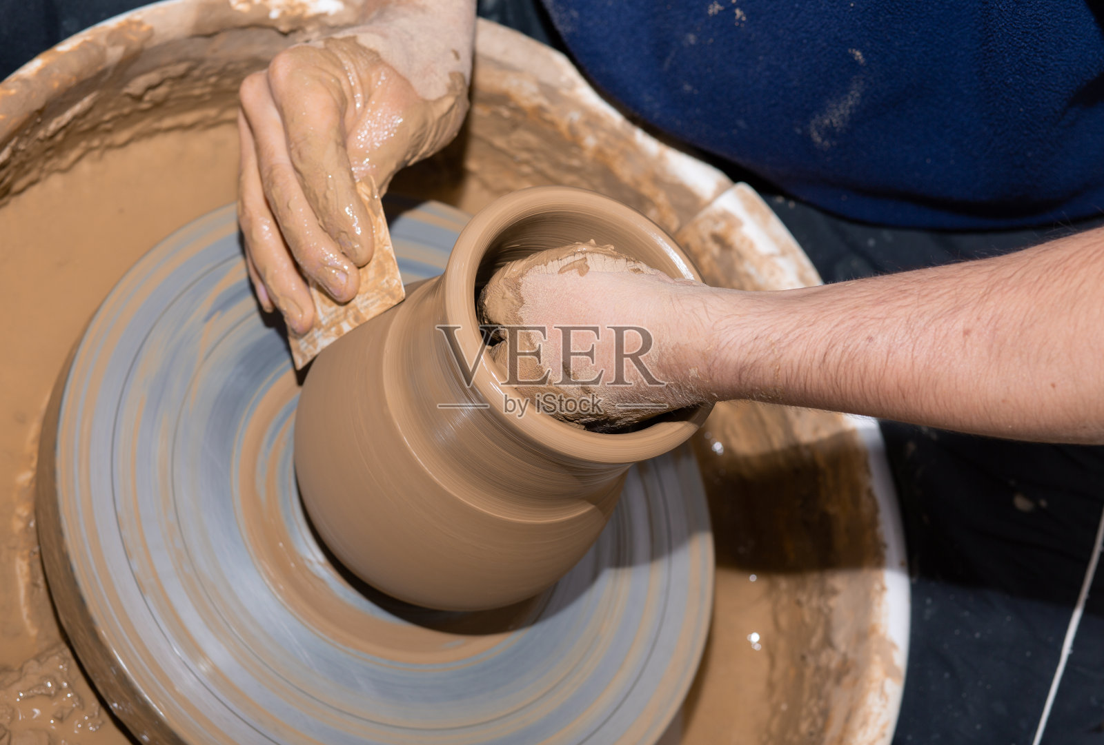 男子双手在陶轮上制作陶罐花瓶。塑造花瓶。照片摄影图片