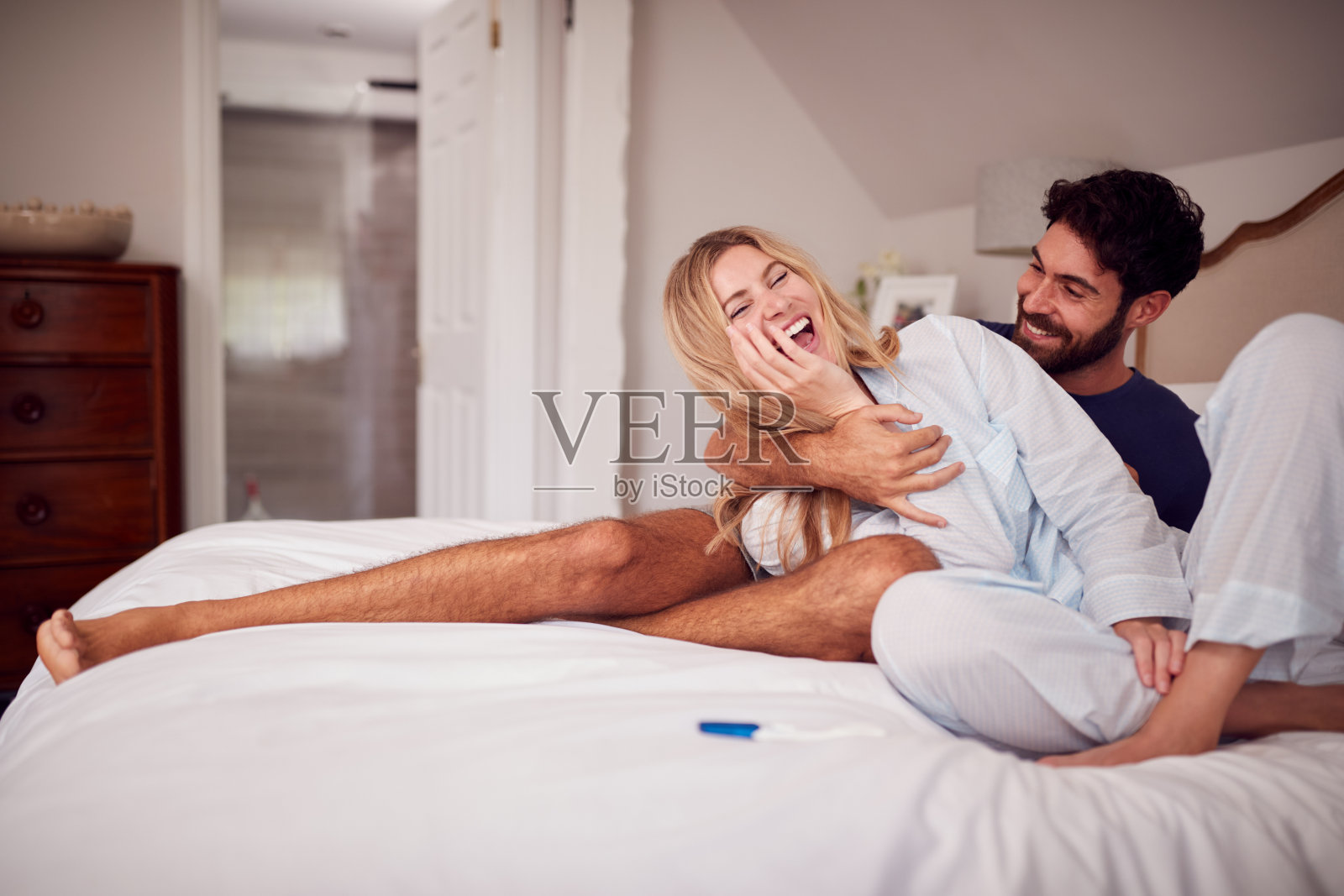 一对穿着睡衣在卧室庆祝验孕阳性的夫妇照片摄影图片
