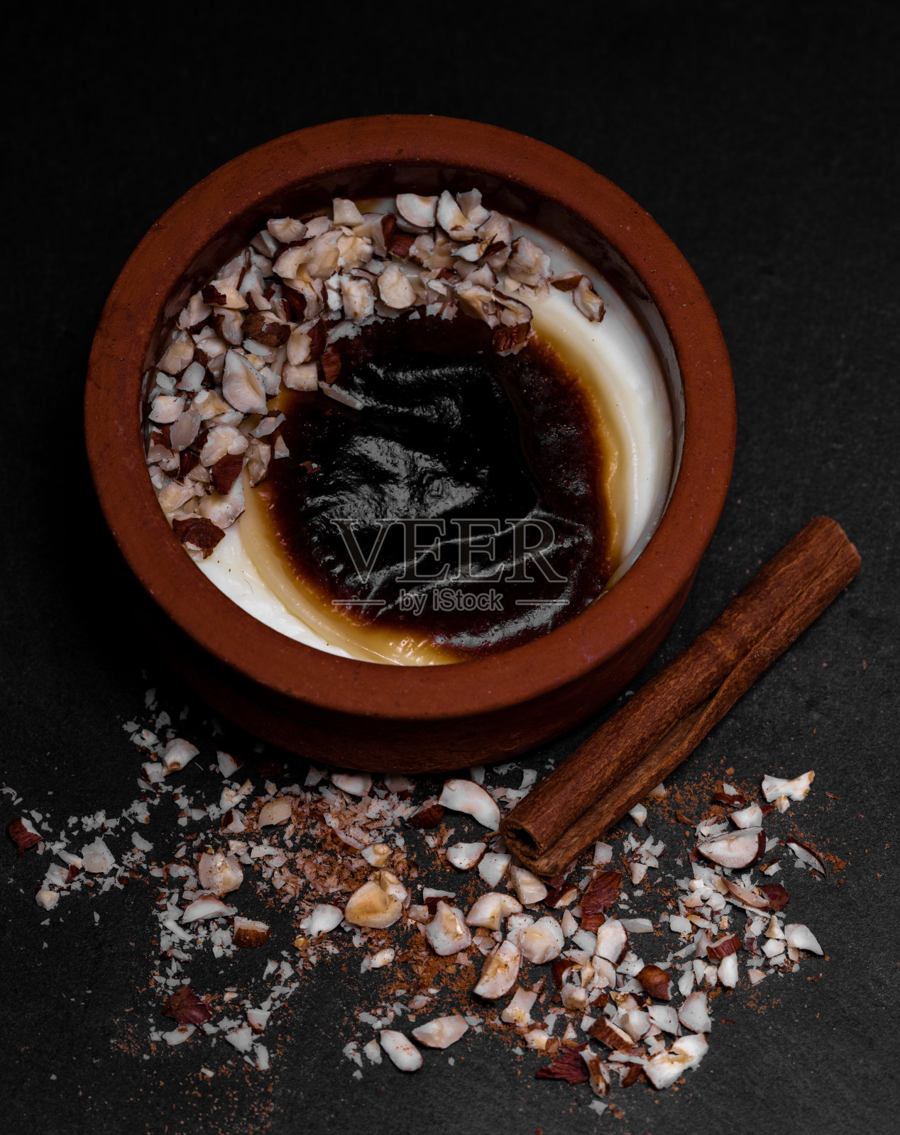 土耳其传统的砂锅甜点与肉桂棒和榛子;sutlac。烤米饭布丁。照片摄影图片